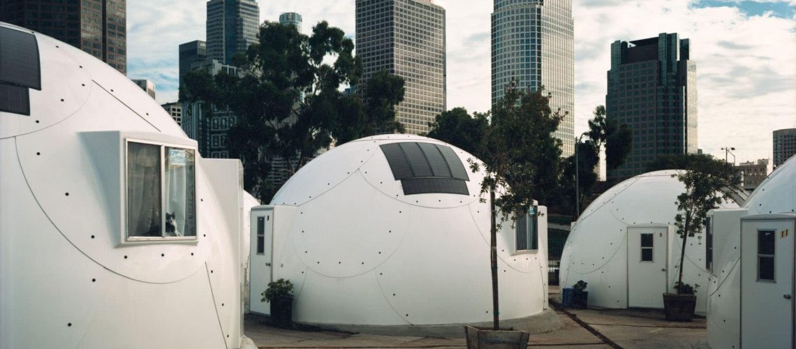 This community of experimental fiberglass domes offers transitional housing for as many as thirty-four homeless people. Eight of the domes contain common facilities, including kitchens, bathrooms, laundries and computer rooms. The other twelve provide shelter for single individuals or families. Activist Ted Hayes founded the village in 1993 as alternative for the many homeless people who are afraid of shelters. The domes allow greater privacy for the people who stay in them, and the village itself acts as a microcosm of society, providing residents with a setting in which they may stabilize their lives and garner the skills necessary to reenter the “real world.”

With their distinctive design, the domes are meant to call the attention of passing motorists on the nearby Harbor Freeway to the problem of homelessness. Initial funding for Dome Village was provided by the Atlantic Richfield Oil Company.

Ted Hayes has a long history of promoting innovative ways to help the homeless that incorporate problem-solving and individual responsibility. He is sometimes referred to as the “Rasta Republican.” In the 1980s he started a cricket team made up of Latino teenagers and homeless men, “Homies and Popz.” The team has played at Windsor Castle and is the subject of a forty-minute operetta commissioned by the Los Angeles Opera.